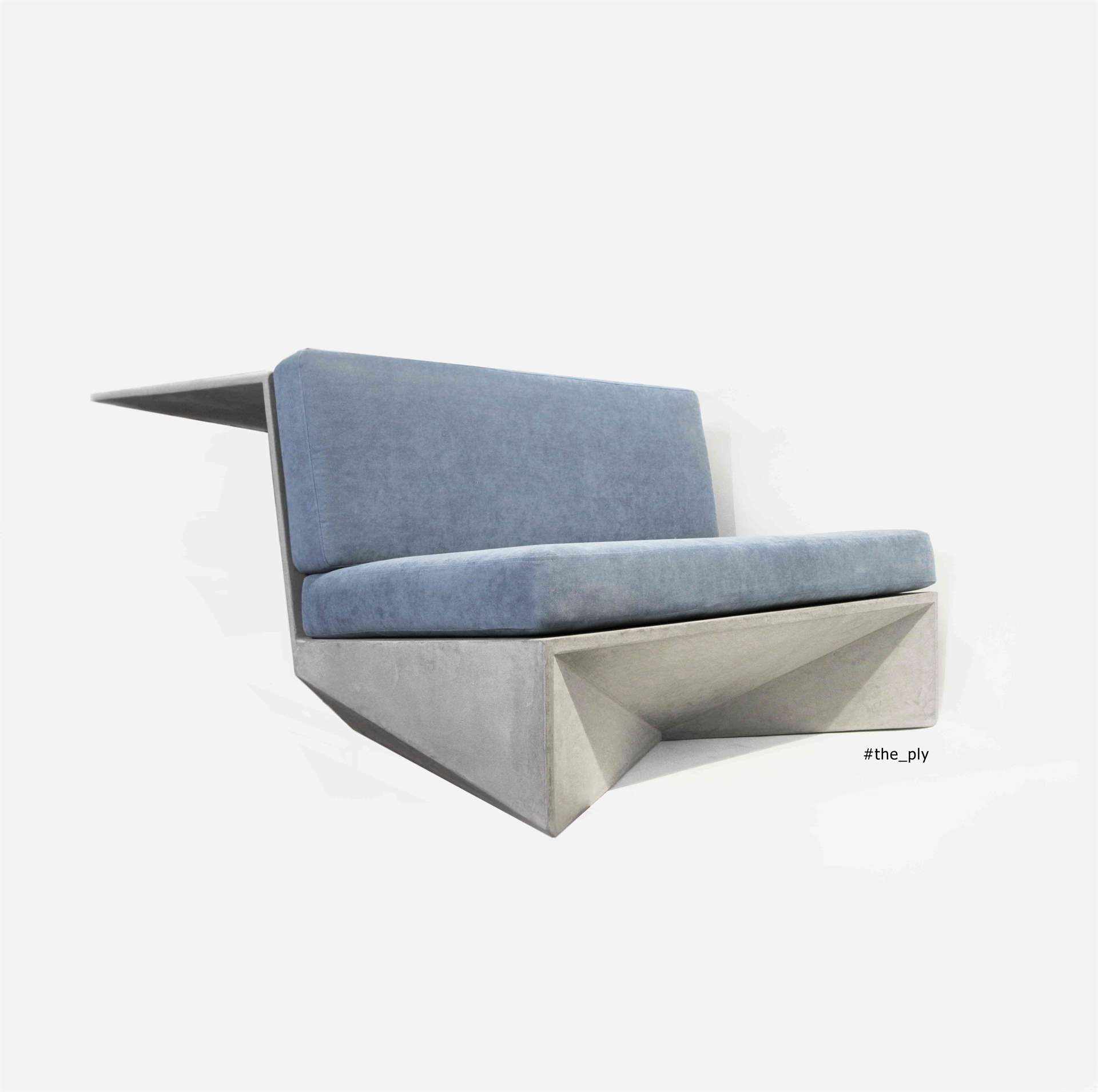Mikrozement-Sofa in Grau mit blauen Kissen.