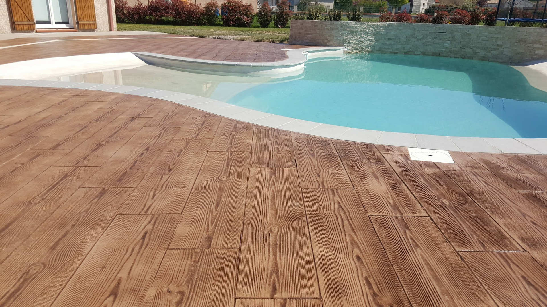 wood imprinted concrete pavement around pool