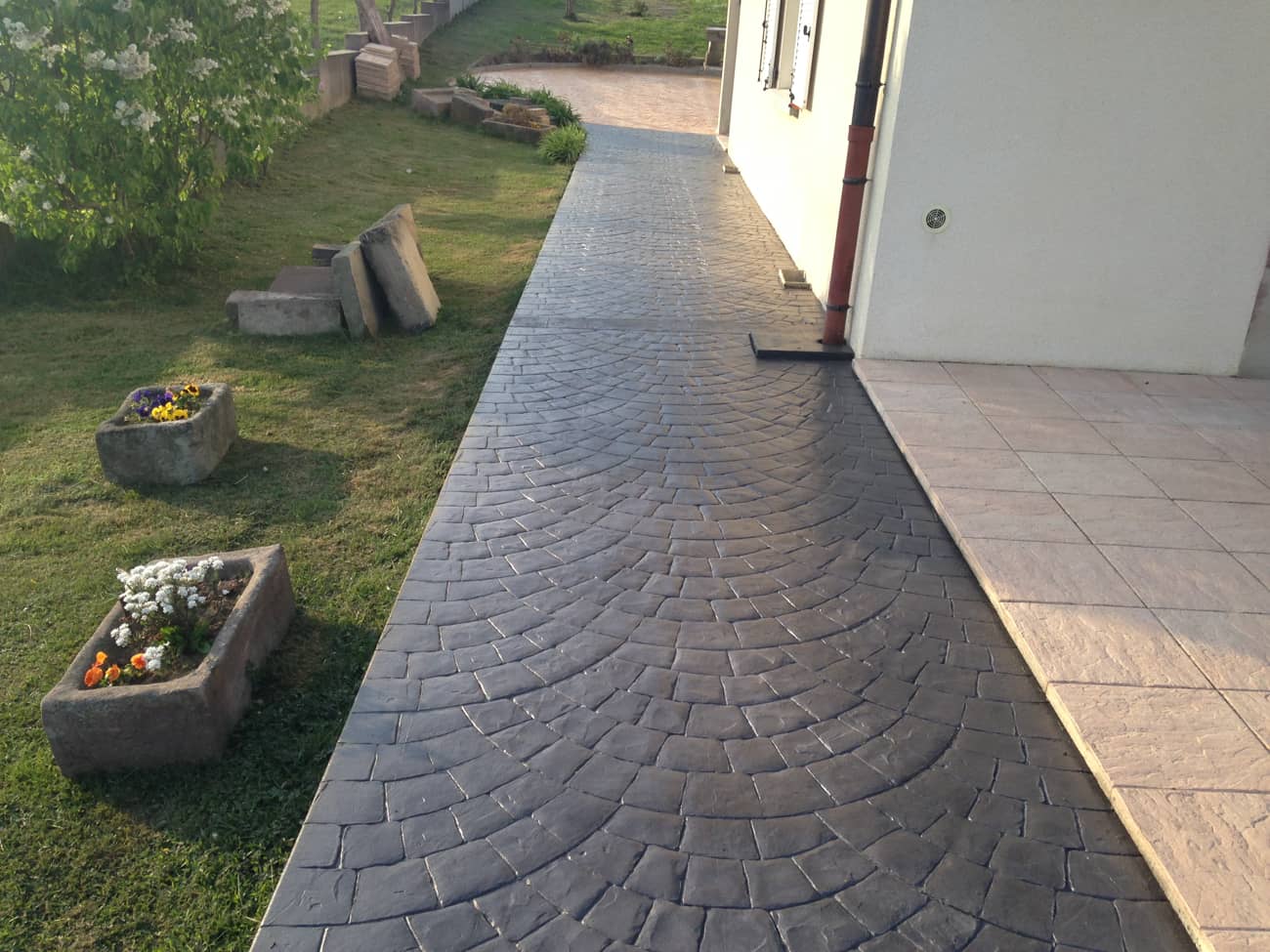 Imprinted concrete in garden next to planters with flowers of different colours