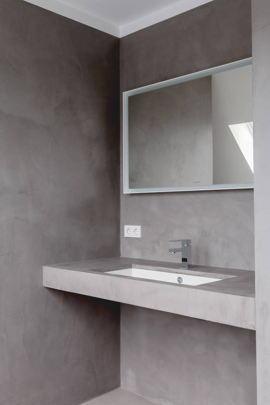 Bathroom with grey microcement on the walls, the floor, and the countertop.