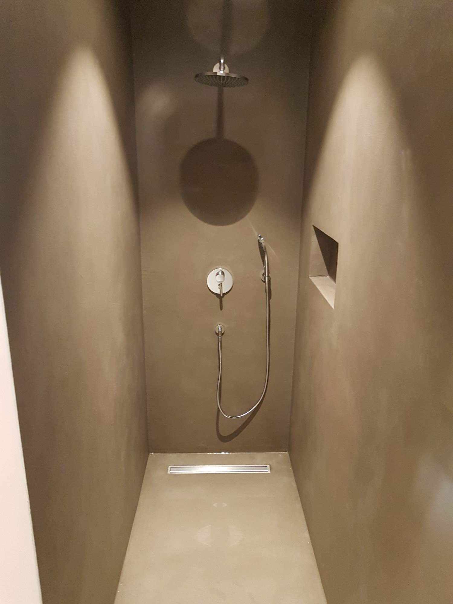 Light microcement coating on shower walls and floor