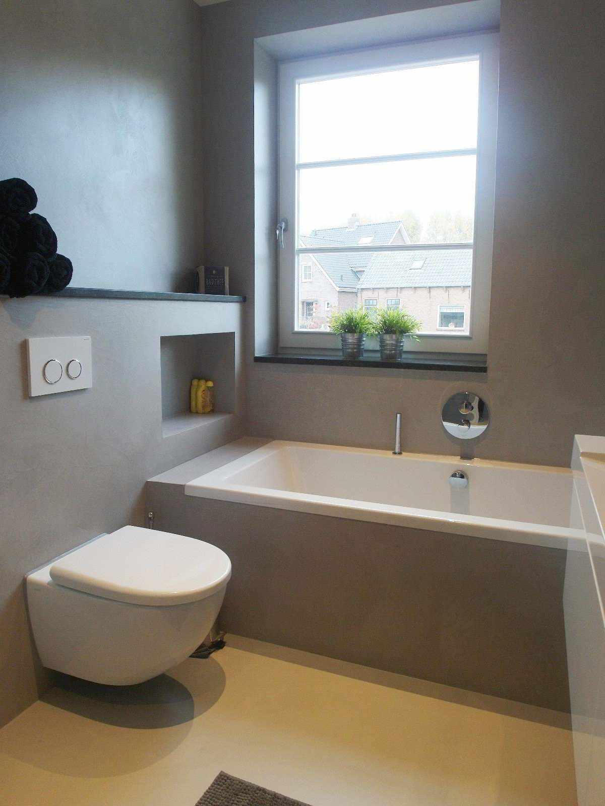 Harmaa mikrosementti seinällä ja kylpyhuonekalusteissa Hollannissa Decas-projektissa.