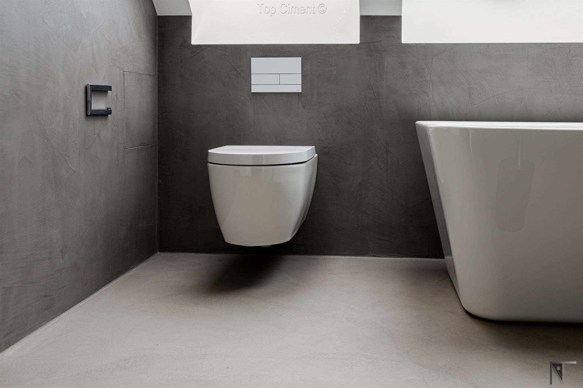 Kylpyhuone, jossa on uusittu laattapinnoitus ja harmaa mikrosementti seinissä ja lattiassa