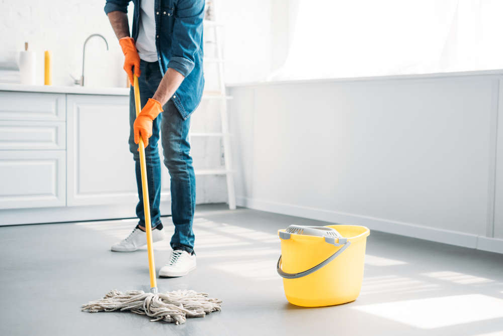 Käyttäjä puhdistaa mikrosementtiä keittiön lattiassa