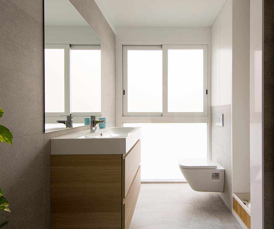 Salle de bain rénovée avec du microciment sur le sol de couleur grise.