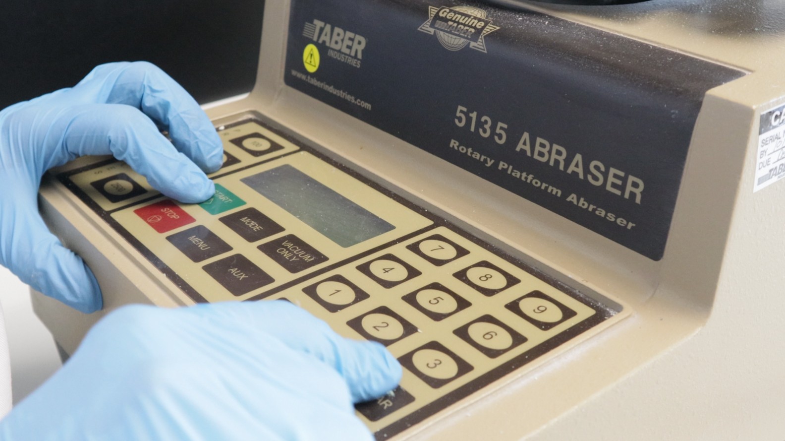 Taber Abraser equipment at the Topciment® laboratory performing an abrasion test to measure wear resistance and coating durability.