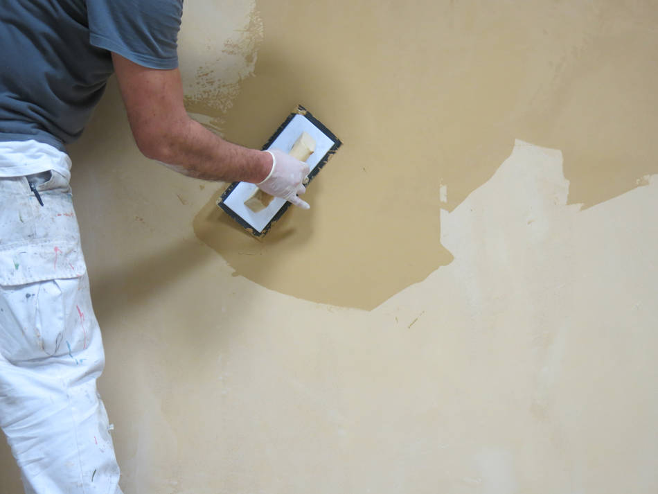 專業人士用橡膠抹刀在牆上塗抹微水泥